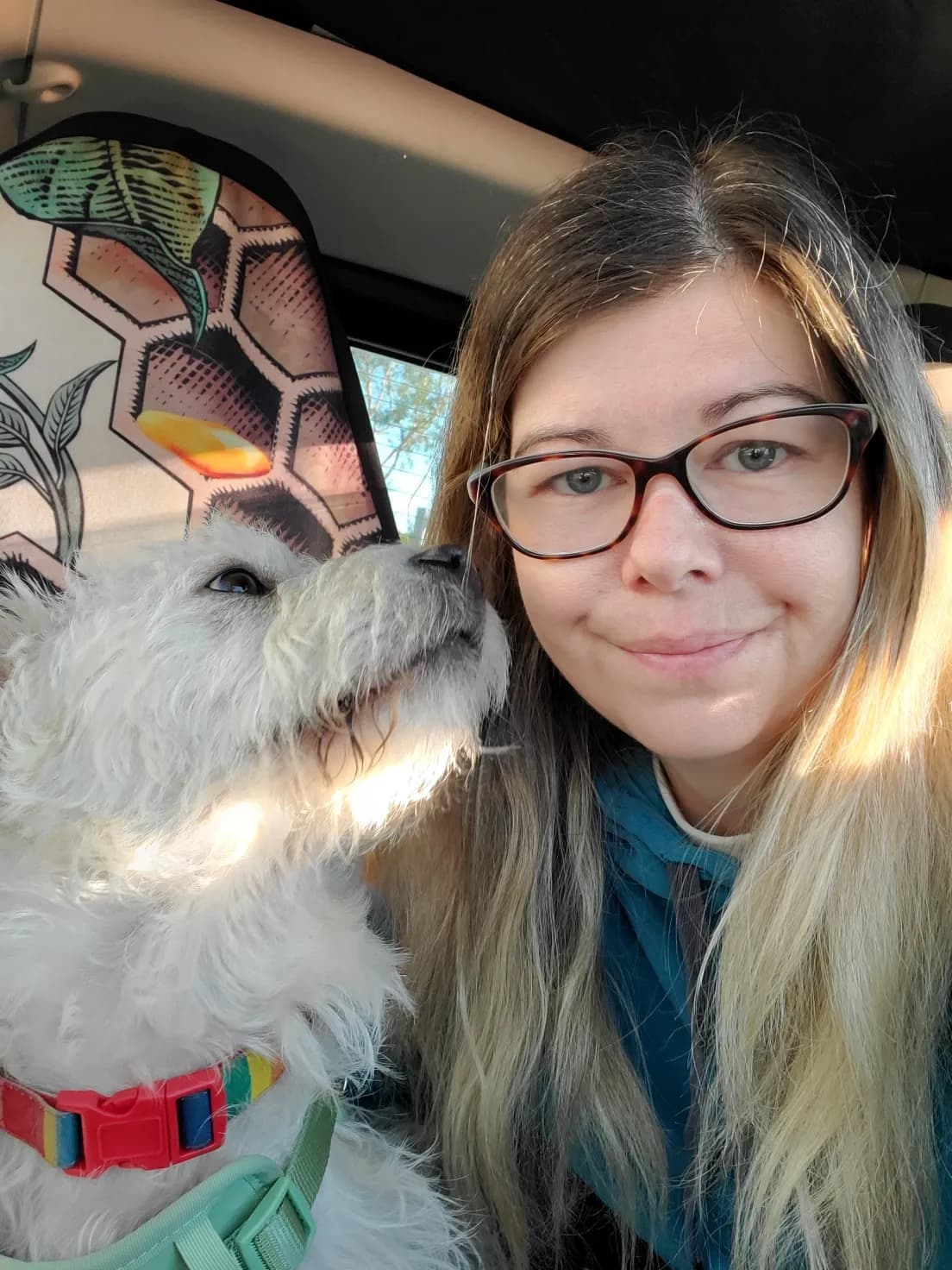 Sarah smiling cheek to cheek with a fluffy white pup